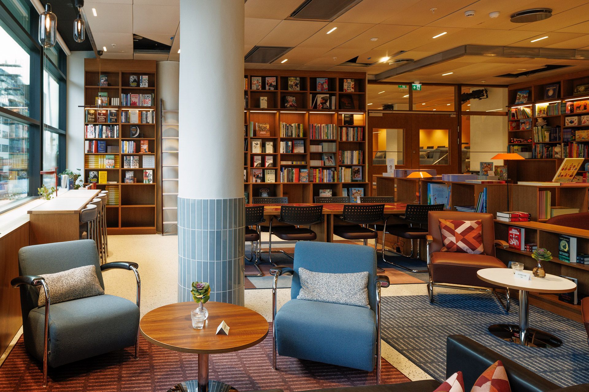 Koselig bibliotekstue med lenestoler, bokhyller og varm belysning