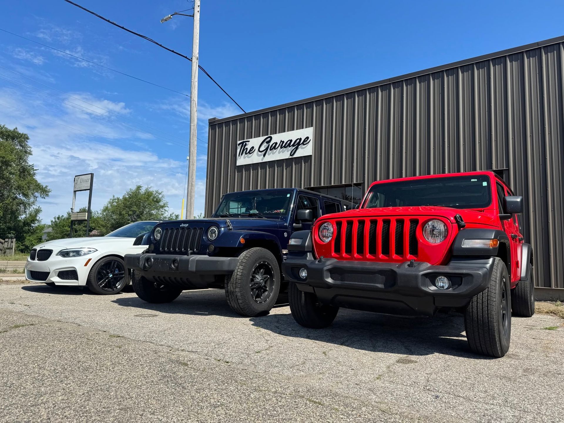 Three parked Jeeps outside a building under a blue sky | The Garage MKG