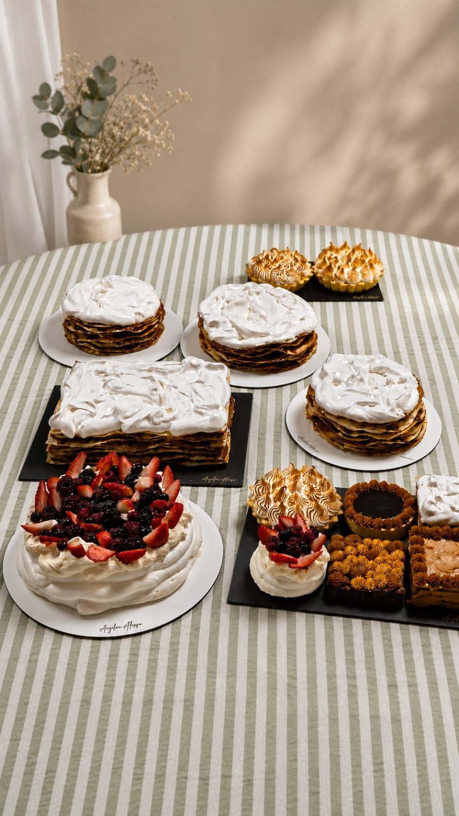 Surtido de pasteles espolvoreados con azúcar glas y tartas con frutos rojos dispuestas sobre un mantel a rayas.