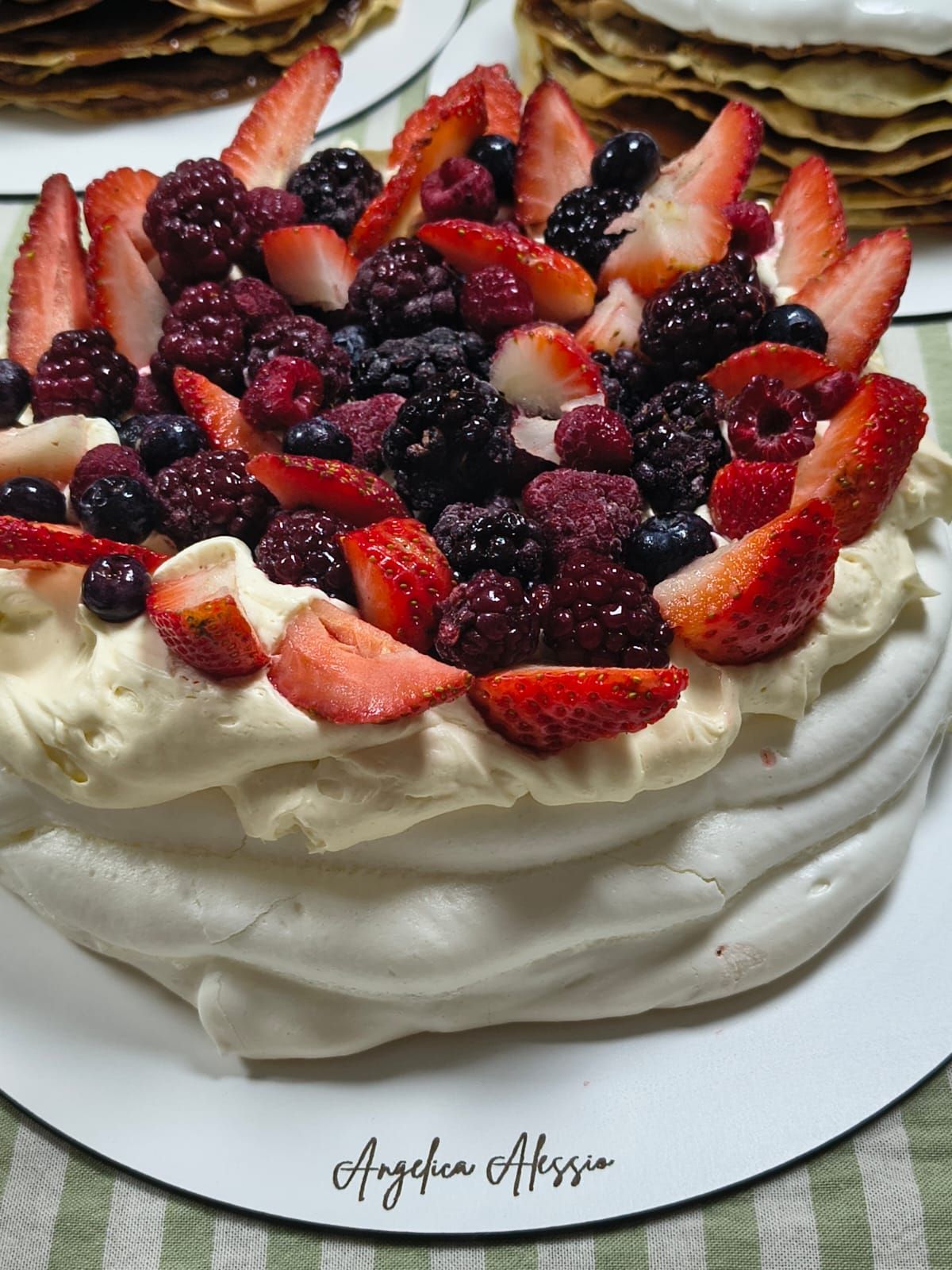 Pastel pavlova con cobertura de frutos rojos: fresas, frambuesas, moras y remolinos de crema.