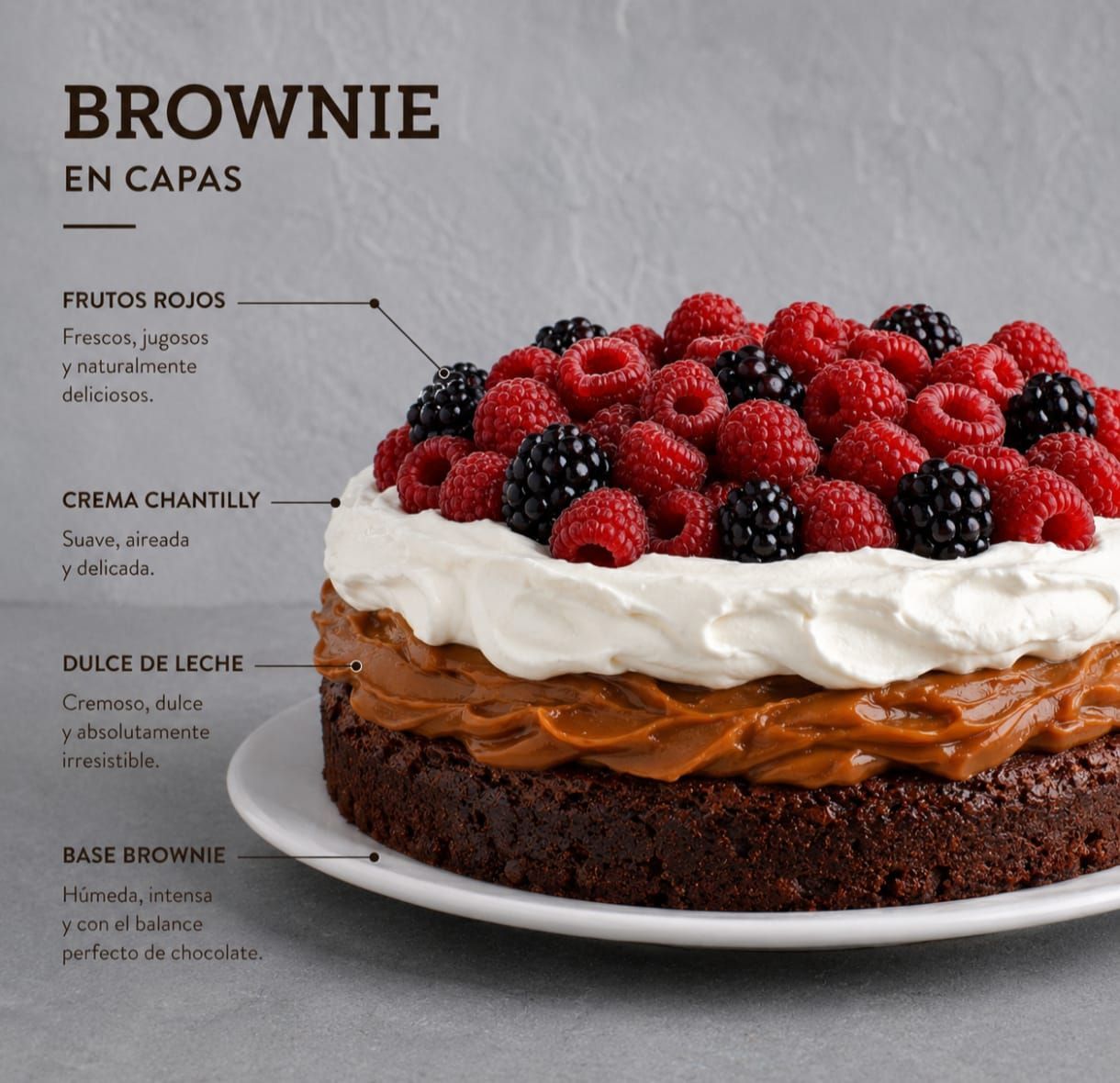 Pastel de brownie en capas con dulce de leche, crema batida y frutos rojos en un plato.