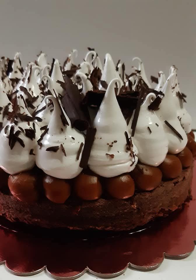 Pastel con cobertura de crema de chocolate sobre una bandeja roja con borde festoneado.