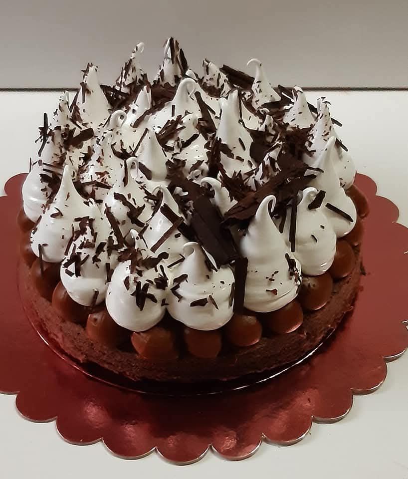 Pastel con cobertura de crema de chocolate sobre una bandeja roja con borde festoneado.