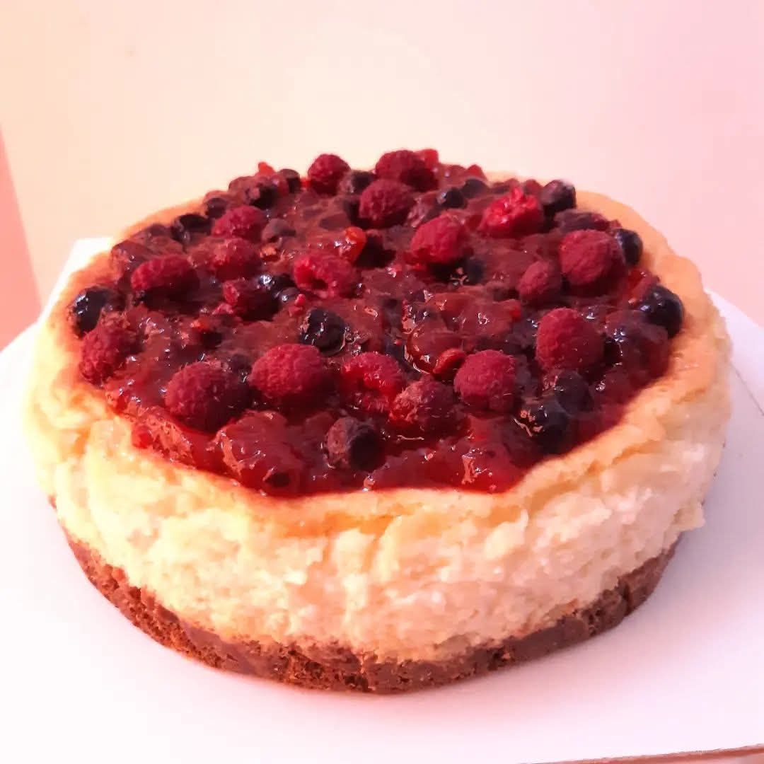 Tarta de queso con frutos rojos sobre un plato blanco.