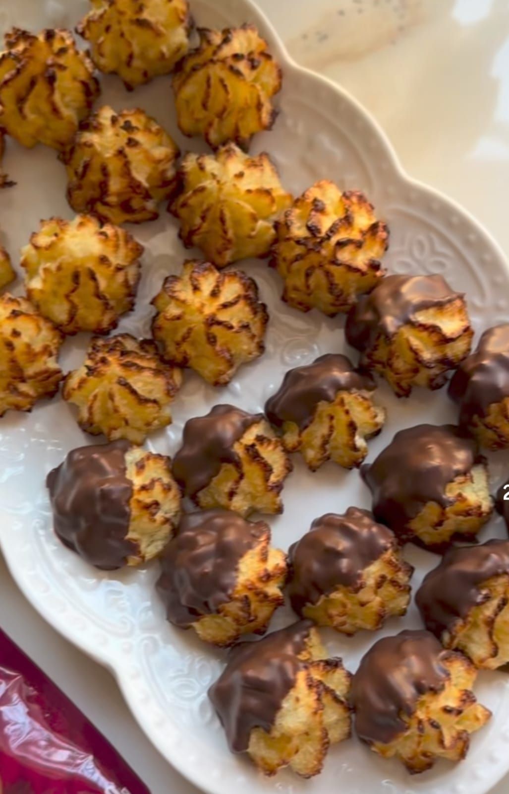 Plato de pequeñas galletas decoradas con manga pastelera, algunas bañadas en chocolate, dispuestas en una fuente blanca.