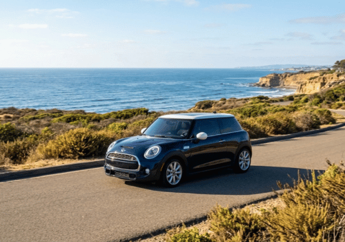Black MINI Cooper driving along a scenic San Diego coastal road