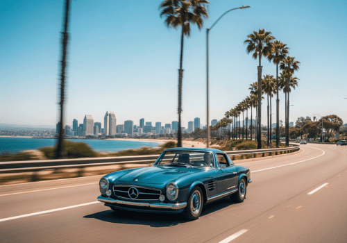 Classic blue convertible driving along a palm-lined coastal road with a city skyline in the distance
