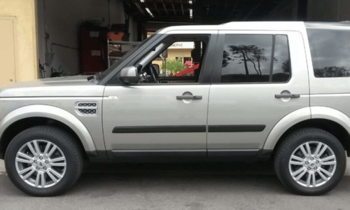 Silver SUV parked in a garage, side view with driver visible inside