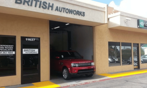 Exterior of British Autoworks car dealership with a red SUV parked under the awning