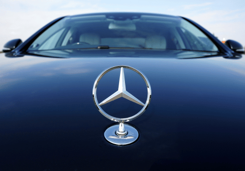 Close-up of a Mercedes-Benz hood ornament on a dark blue car
