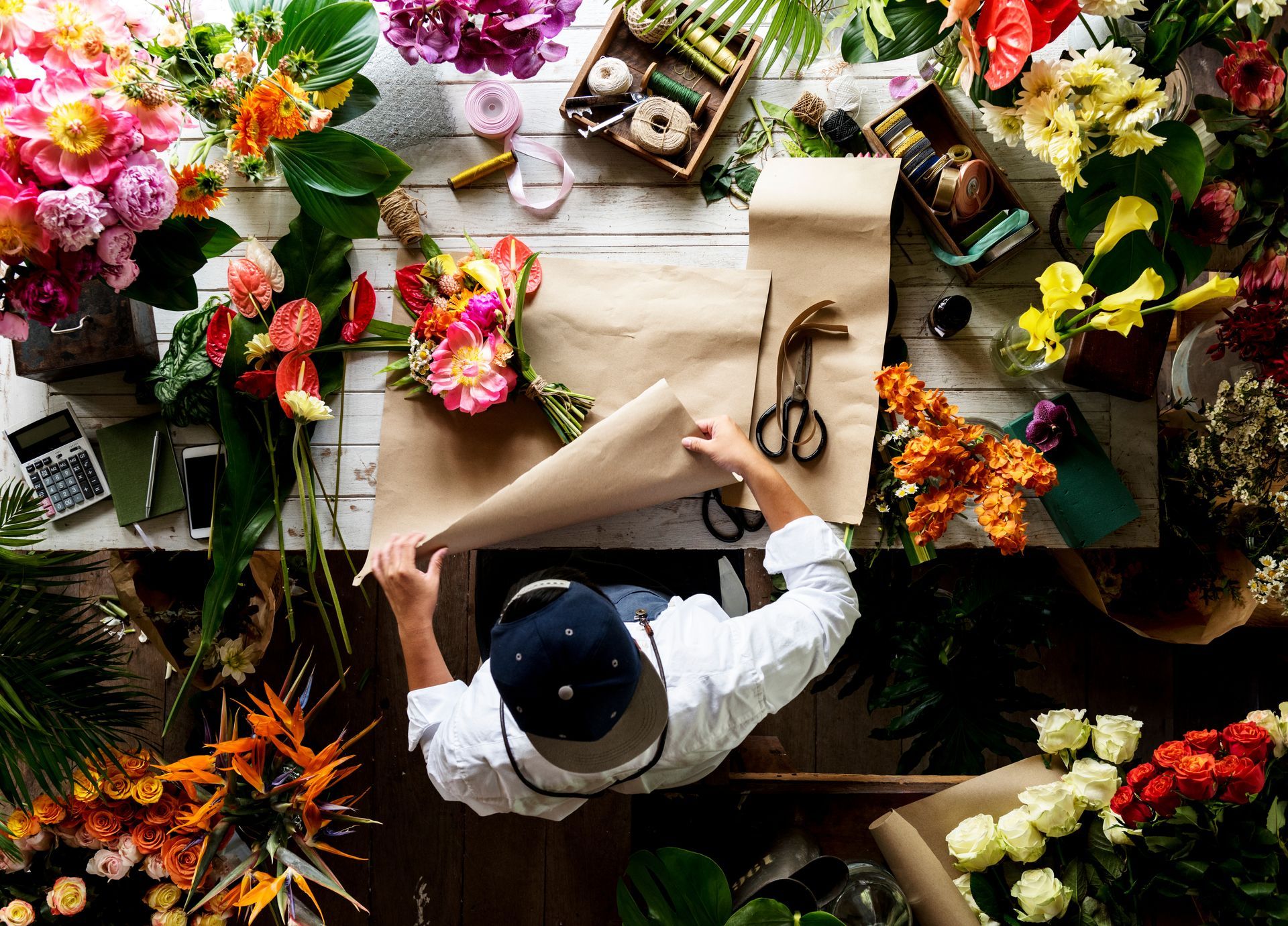 Overhead view of fresh flowers and wrapping supplies on a wooden florist shop counter. Overhead view of fresh flowers and wrapping supplies on a wooden florist shop counter.