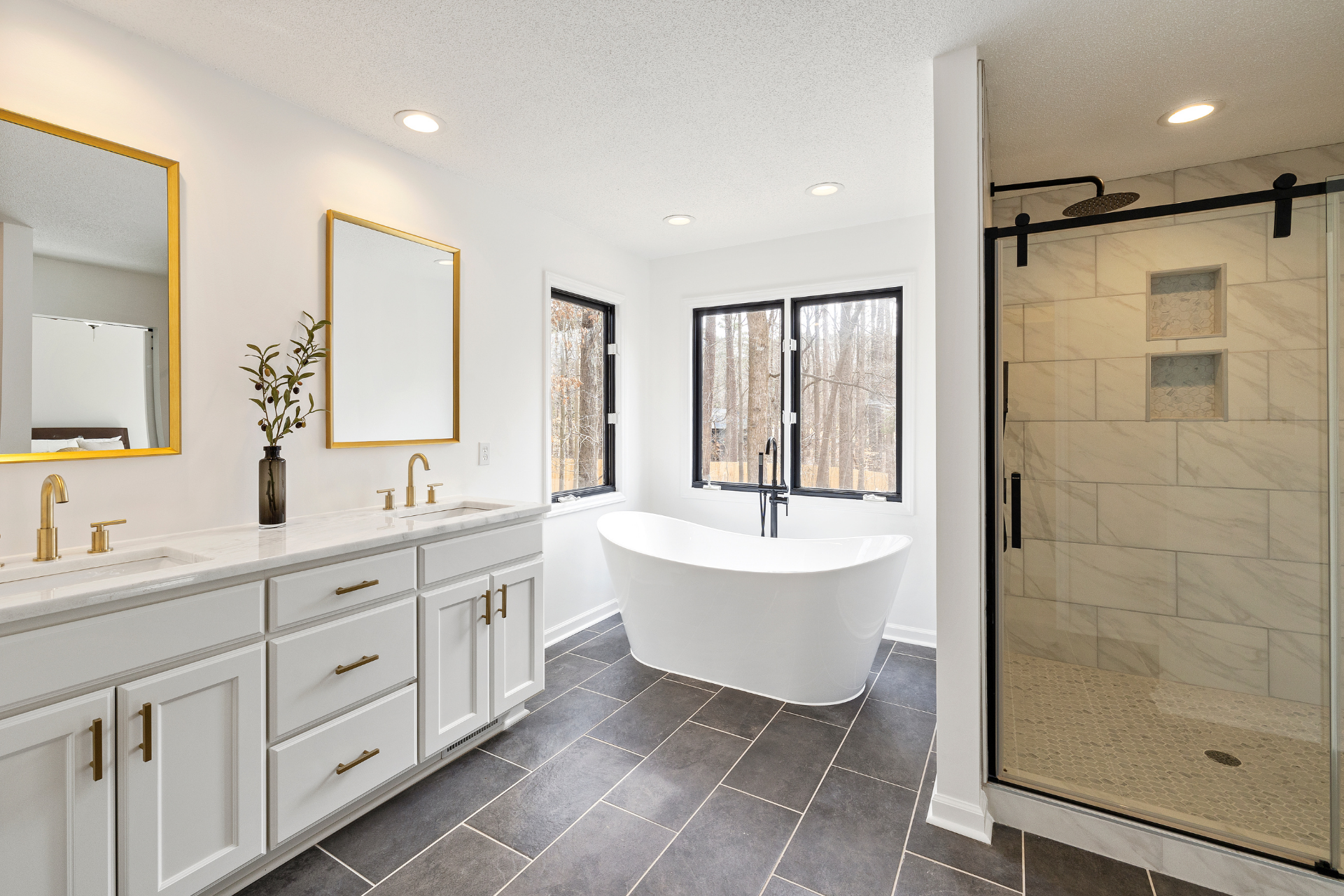 Modern bathroom with white vanity, freestanding tub, tiled floor, and glass shower