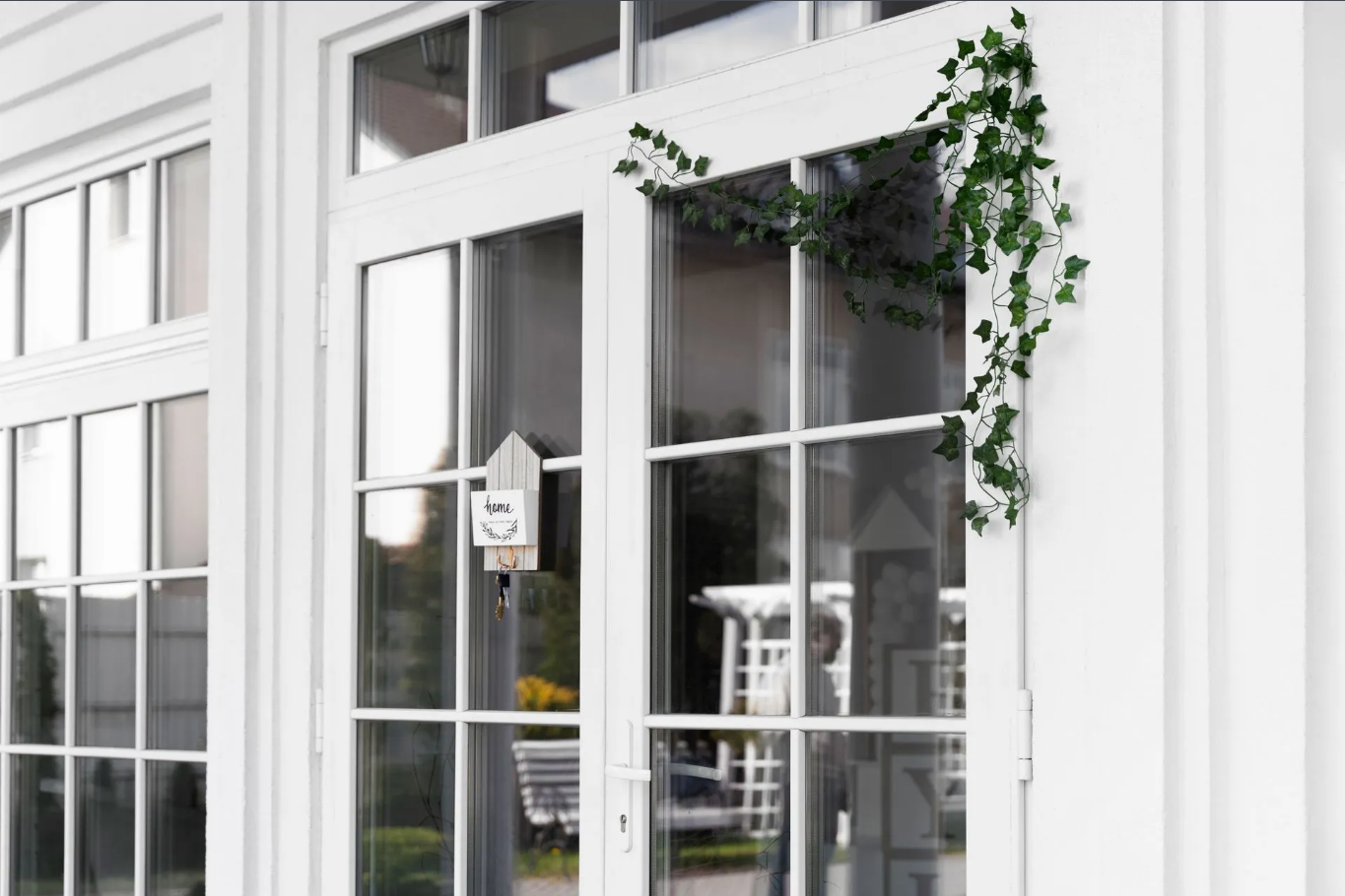 White French doors with decorative greenery and a small wooden birdhouse.