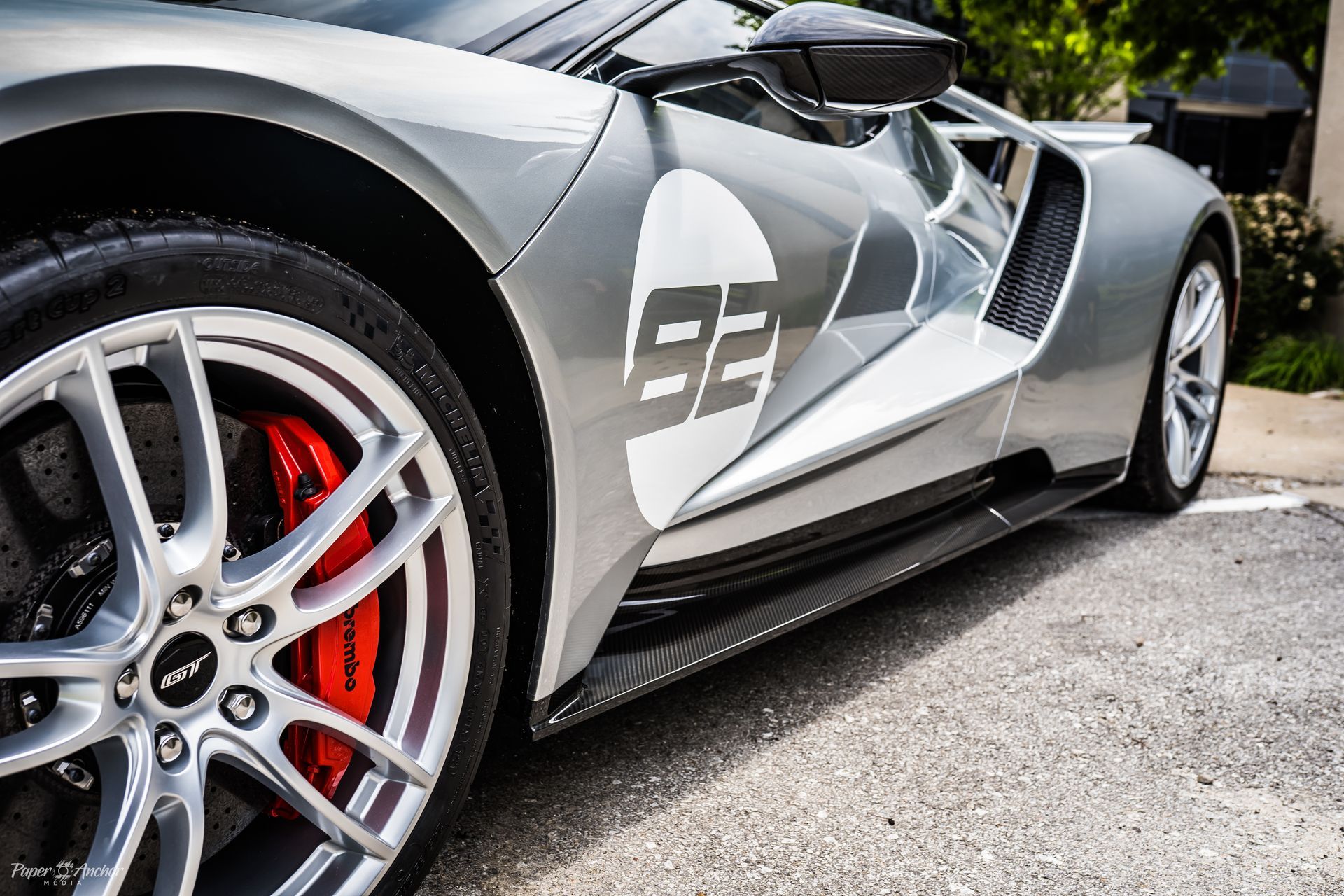A silver sports car with the number 93 on the side is parked in a parking lot.