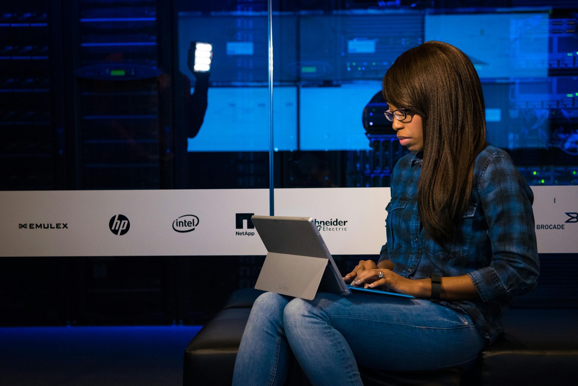 A woman is sitting on a couch using a laptop computer.