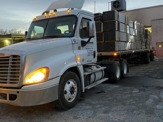A white semi truck is carrying a load of boxes