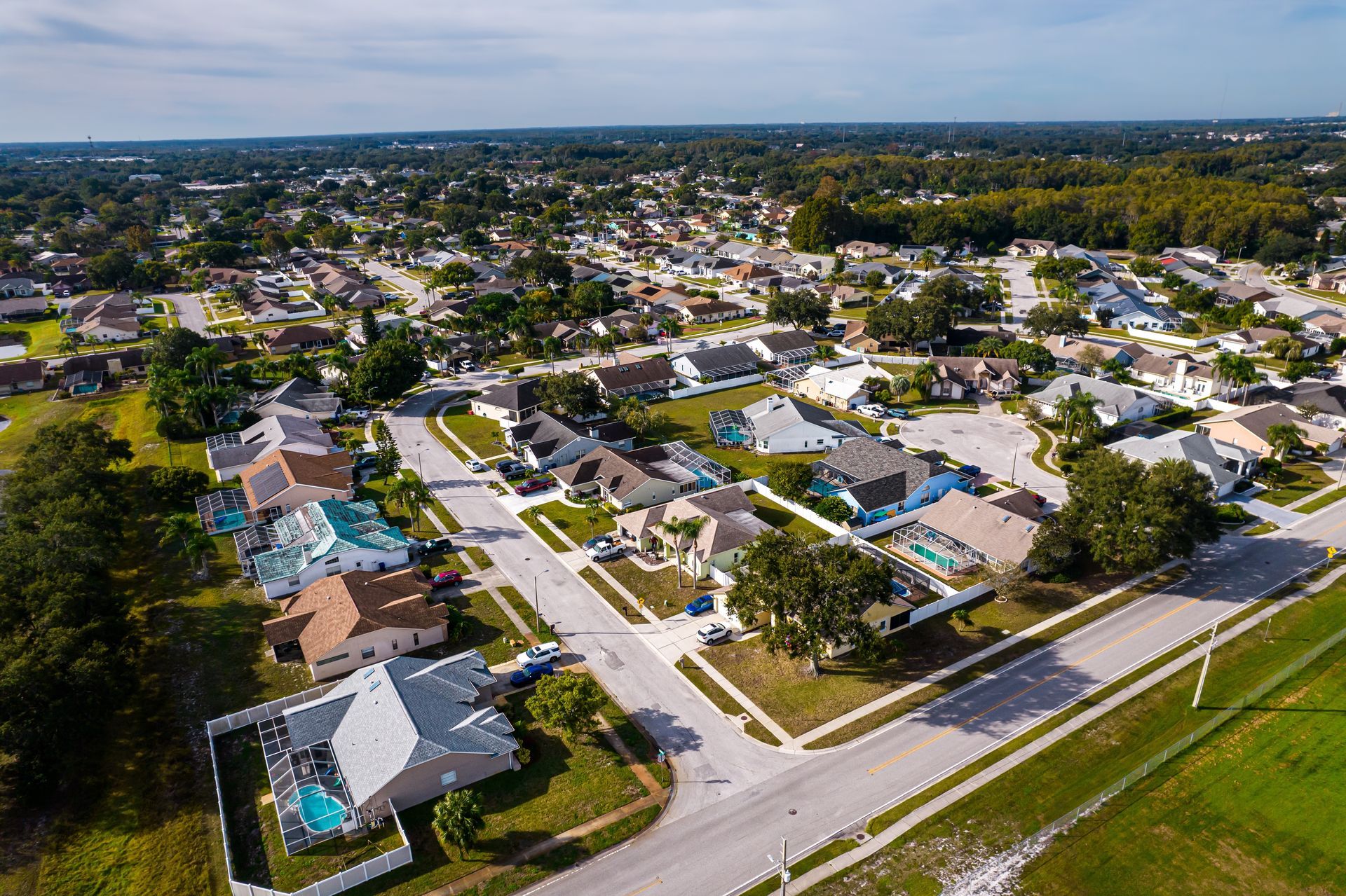 Aerial view of a suburban neighborhood with houses, streets, and trees under clear skies