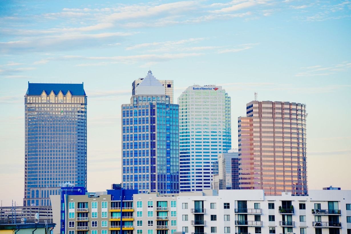 City skyline with modern blue and tan high-rise buildings under a clear sky