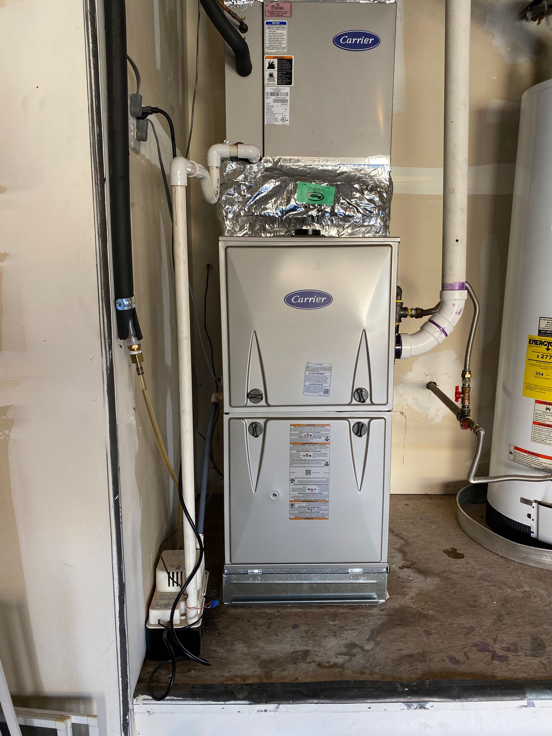 A furnace is sitting in a room next to a water heater.