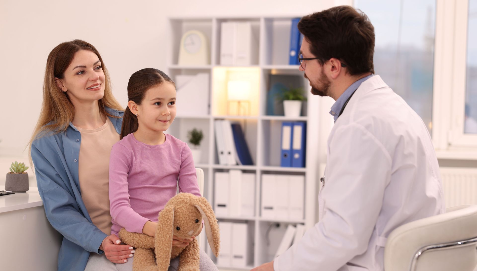Doctor speaking with a mother and child during a primary care visit. Doctor speaking with a mother and child during a primary care visit.