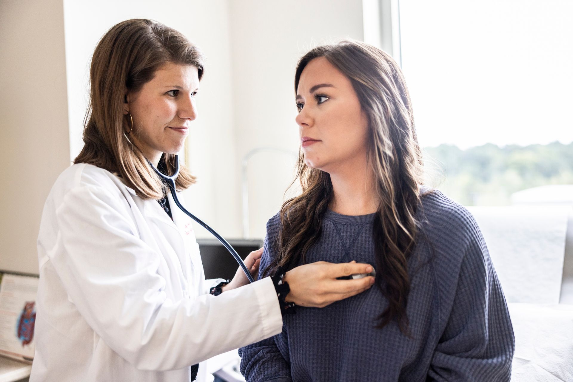 Female doctor as Primary Healthcare Provider listening to patient's heart in exam room. Female doctor as Primary Healthcare Provider listening to patient's heart in exam room.