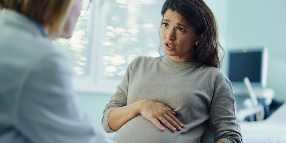 A pregnant woman is talking to a doctor in a hospital room.