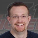 A man with glasses and a beard is smiling for the camera.