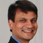 A man in a suit and blue shirt is smiling for the camera.