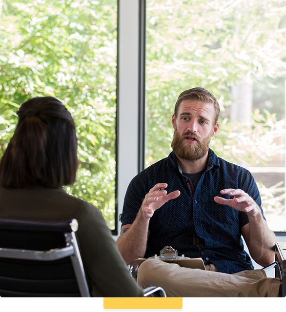 A man and a woman are sitting at a table talking to each other.