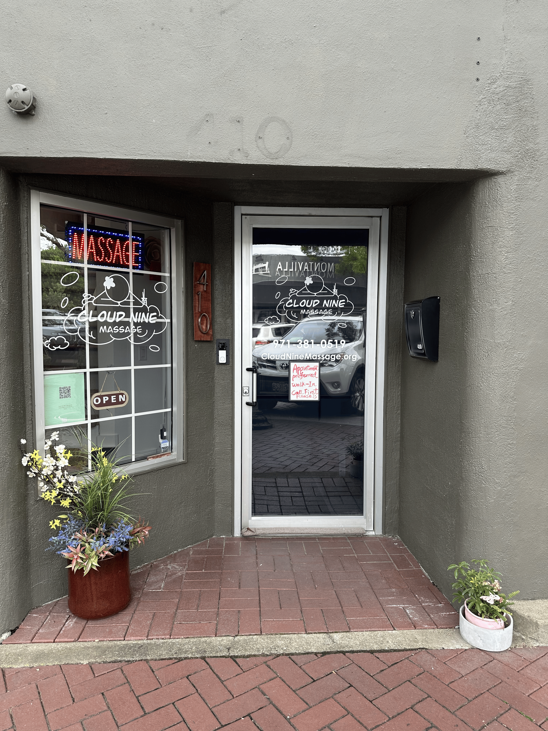 A store front with a glass door and flowers in front of it.