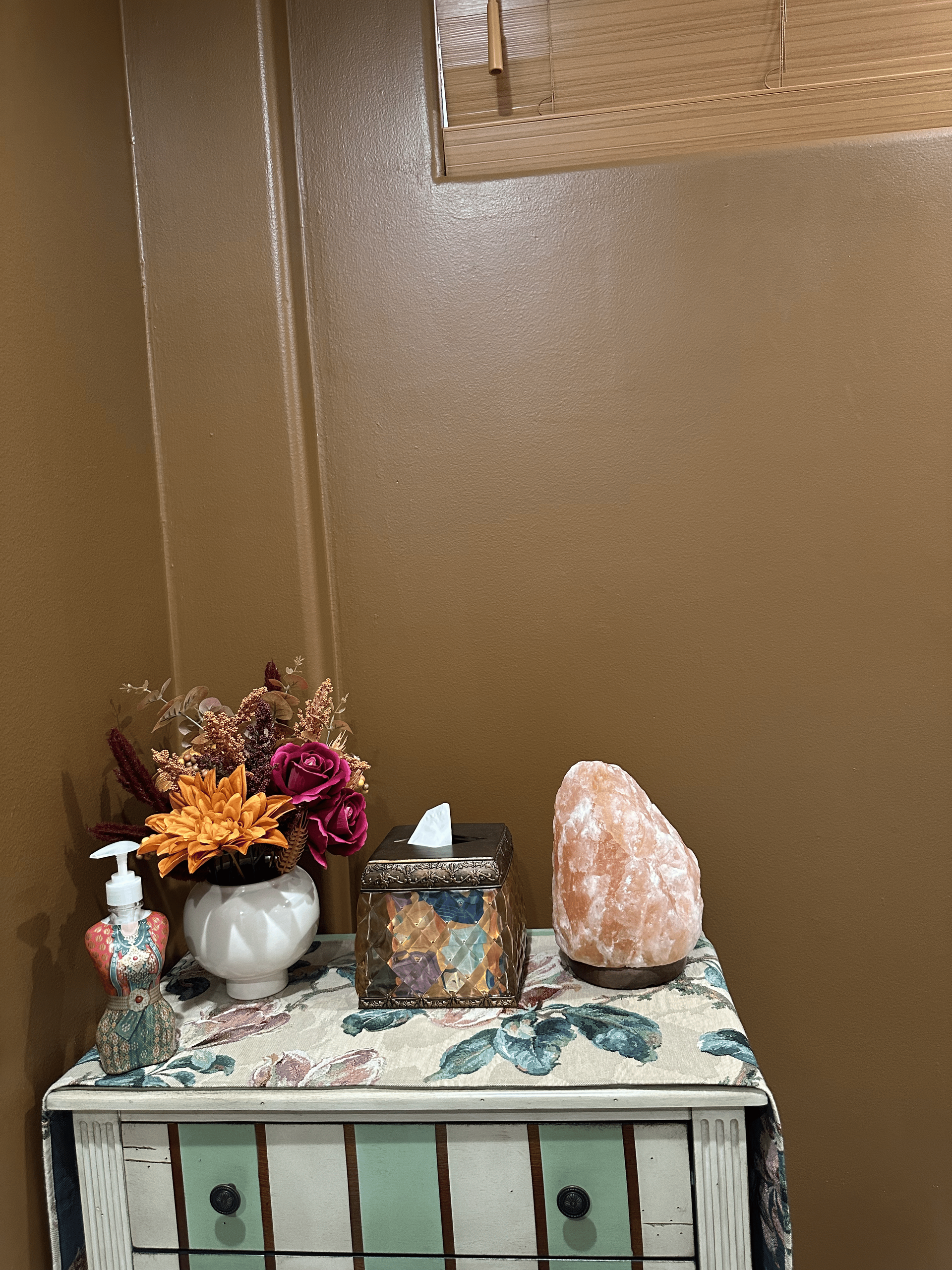 A table with a vase of flowers and a salt lamp on it