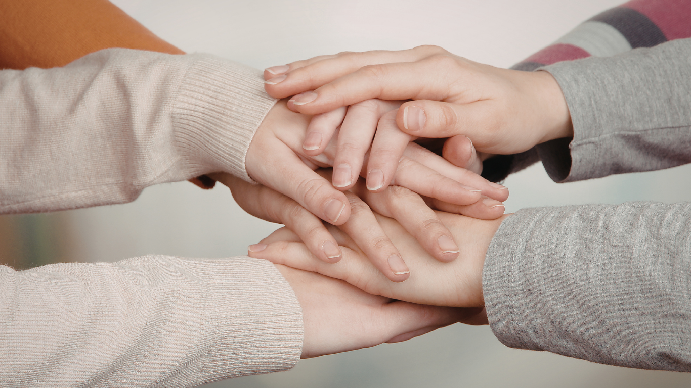 Hands stacked in a pile, symbolizing teamwork and unity.