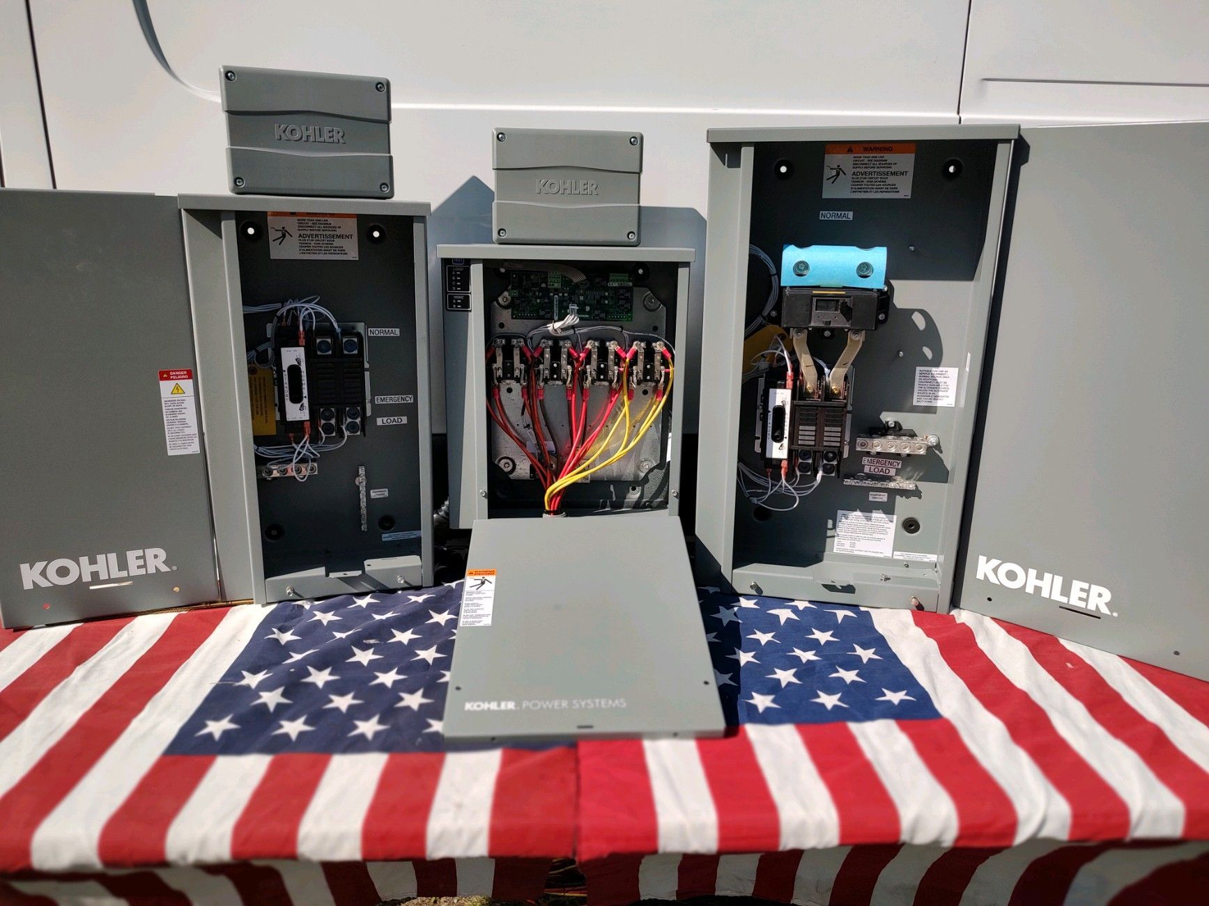 Electrical components and a control panel sit on an American flag. KOHLER branded equipment.