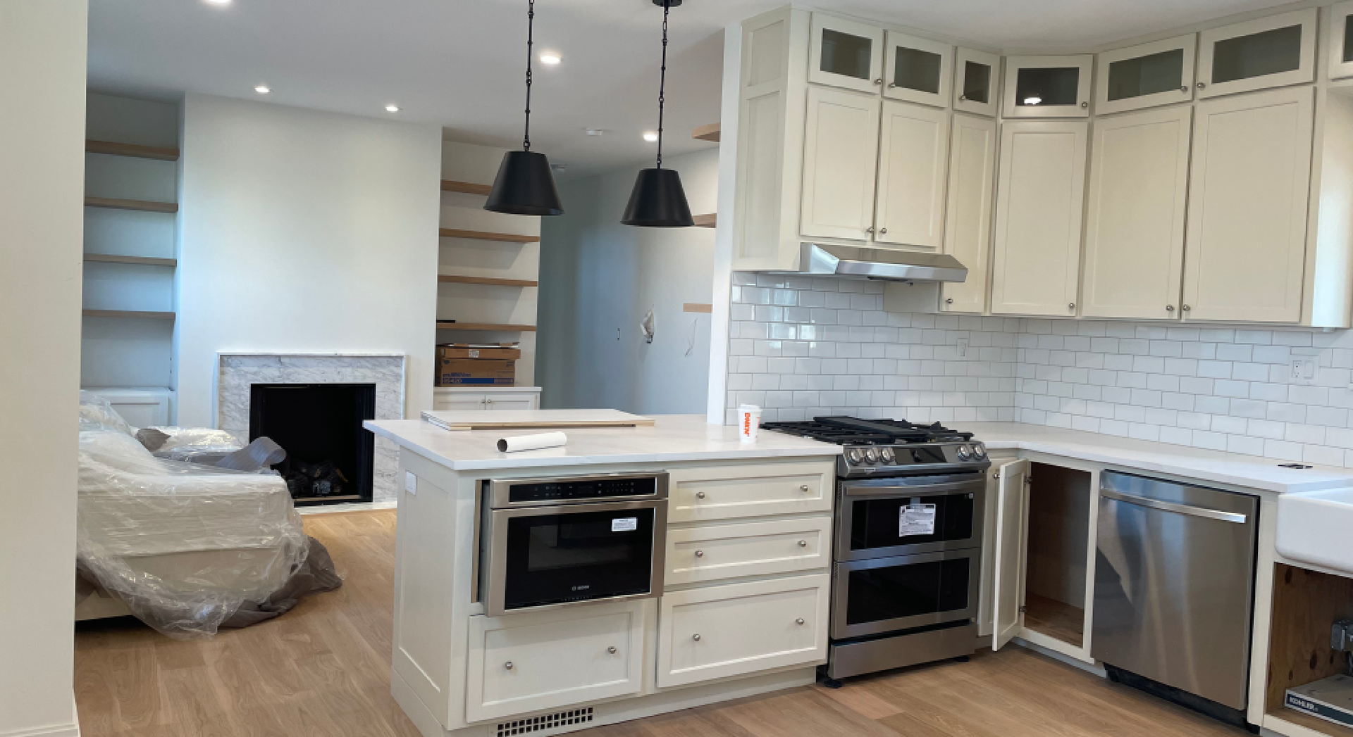 Bright modern kitchen with white cabinets, island, stainless appliances, and light wood floors