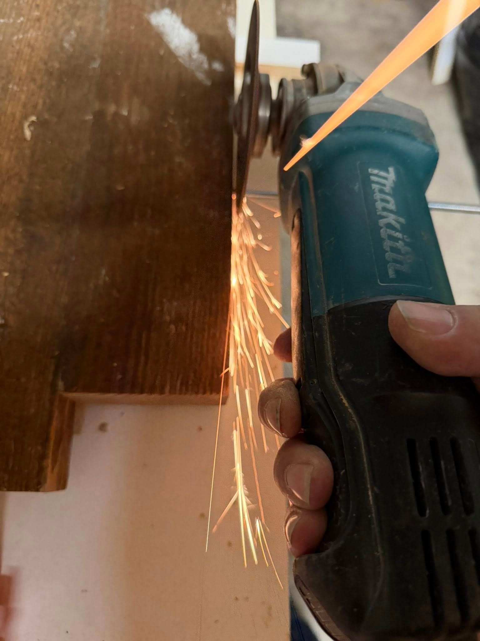 Handheld angle grinder cutting wood, with bright sparks flying from the blade