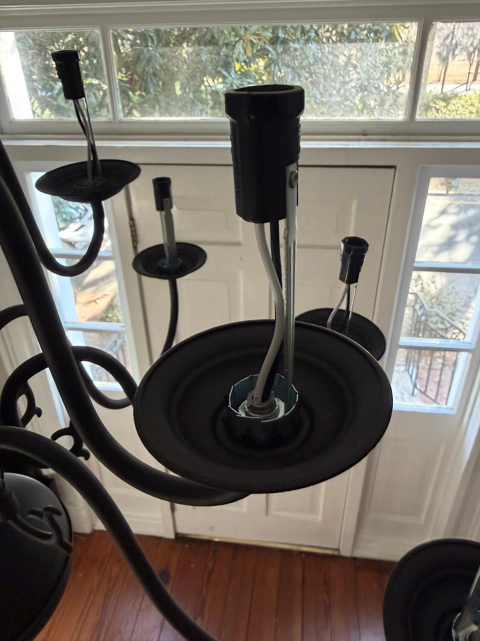 Black chandelier hanging in front of a bright window above a white door