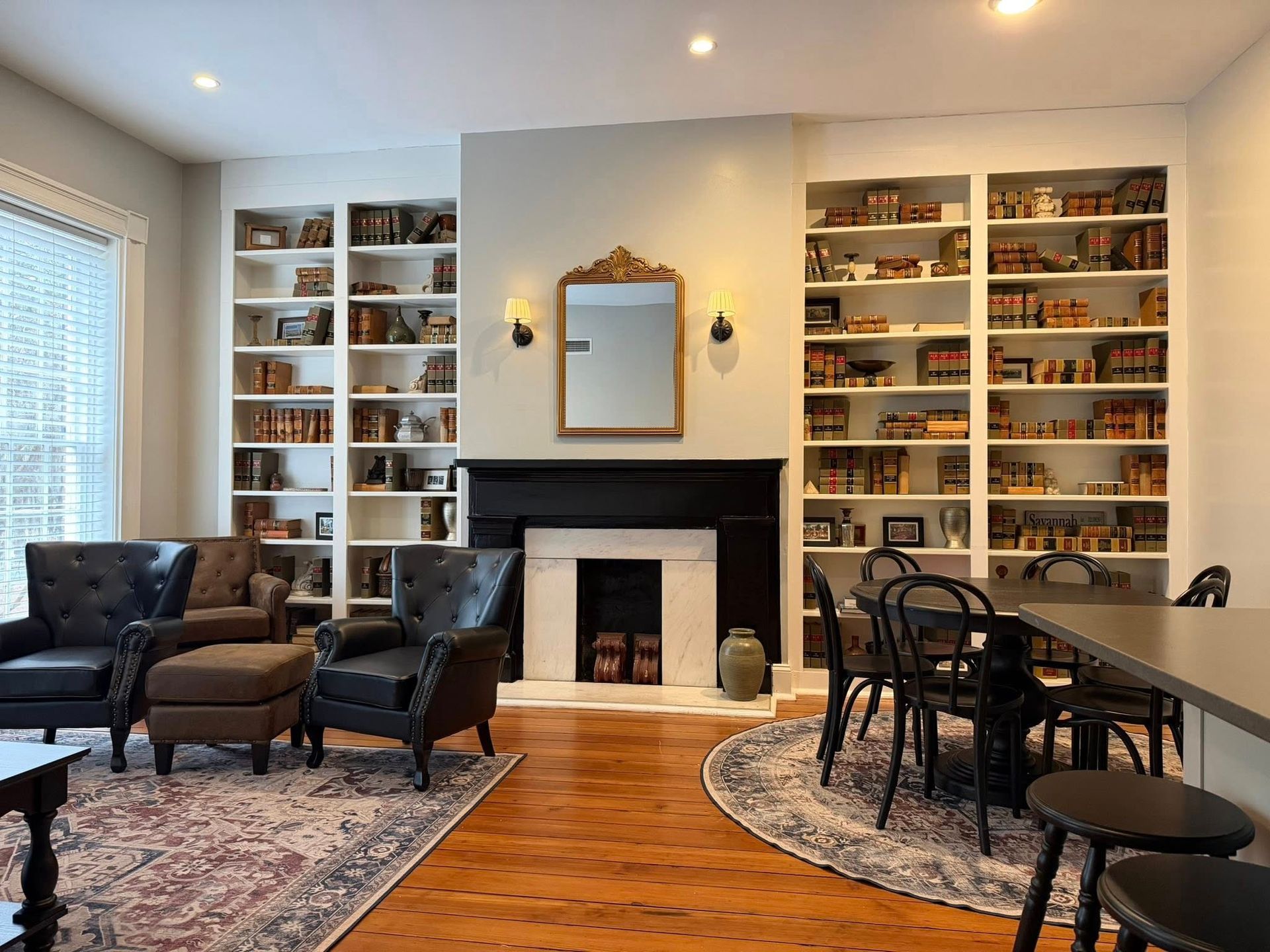Cozy living room with fireplace, built-in bookshelves, armchairs, dining table, and patterned rugs