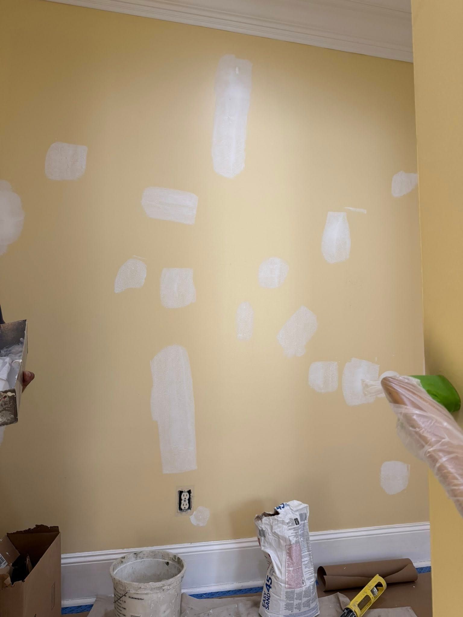 Yellow wall with white spackle patches in a room under repair