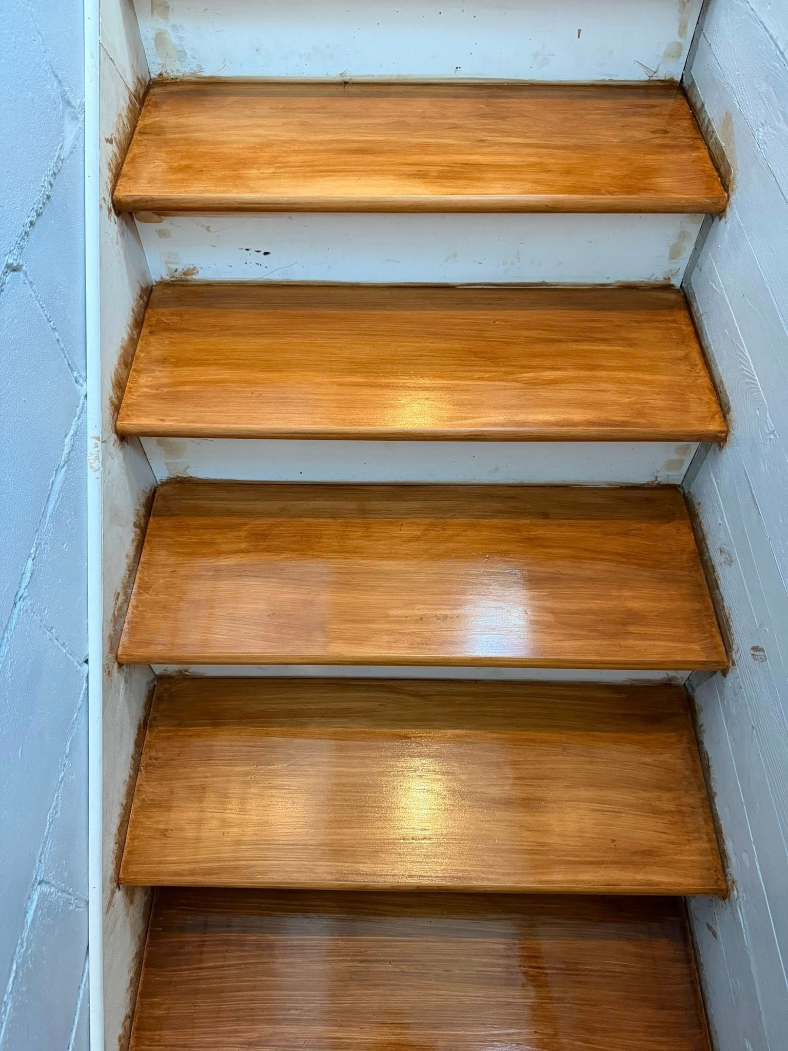 Wooden staircase with five steps and gray side walls, viewed from above