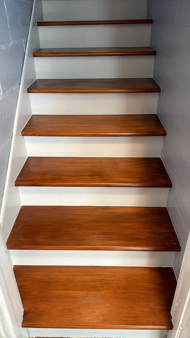 Wooden staircase with white risers and gray side walls, viewed from below.