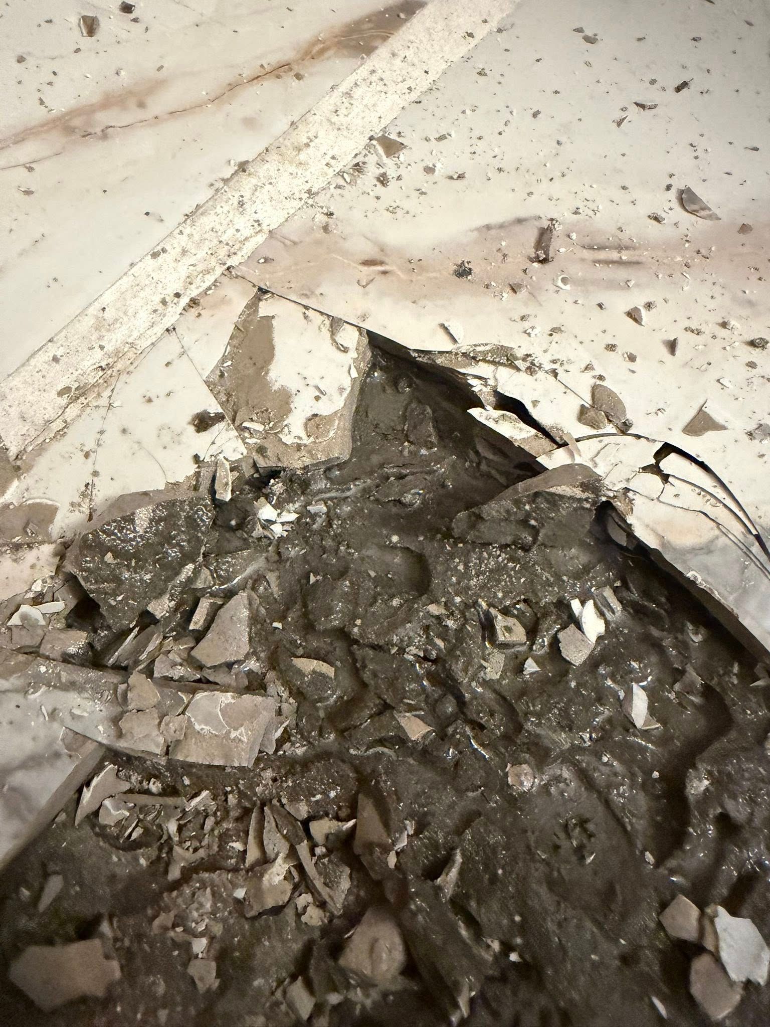 Pile of broken concrete and debris against a white wall on the floor