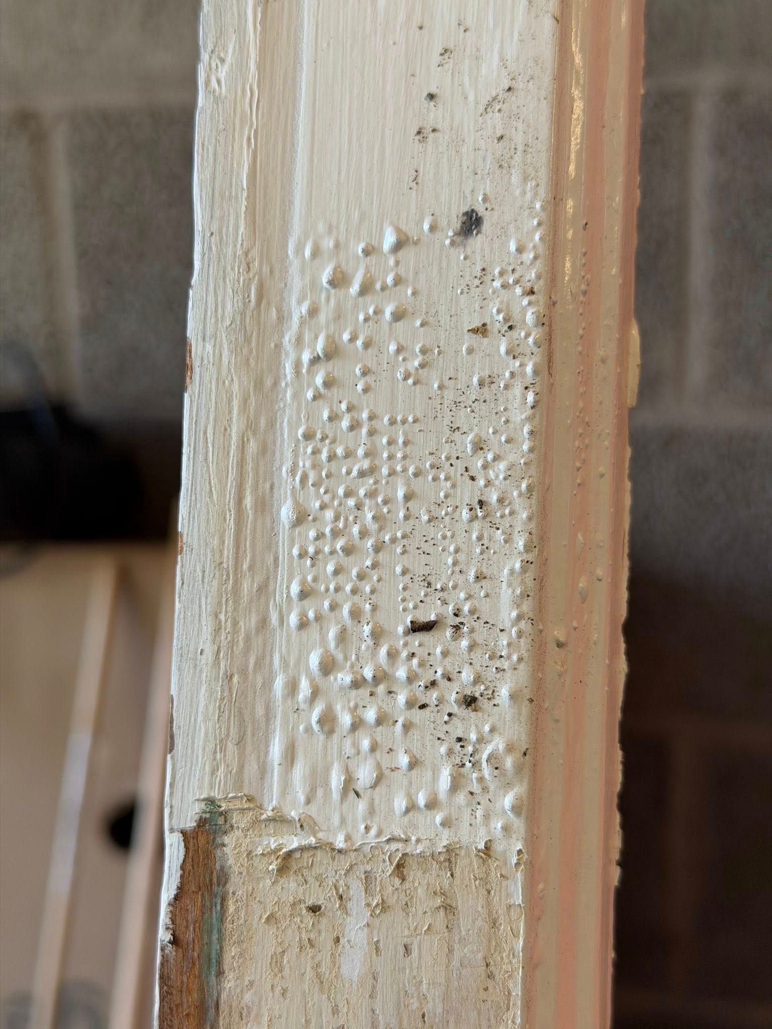 Close-up of a paint-peeled wooden door frame with chipped white paint and exposed wood.