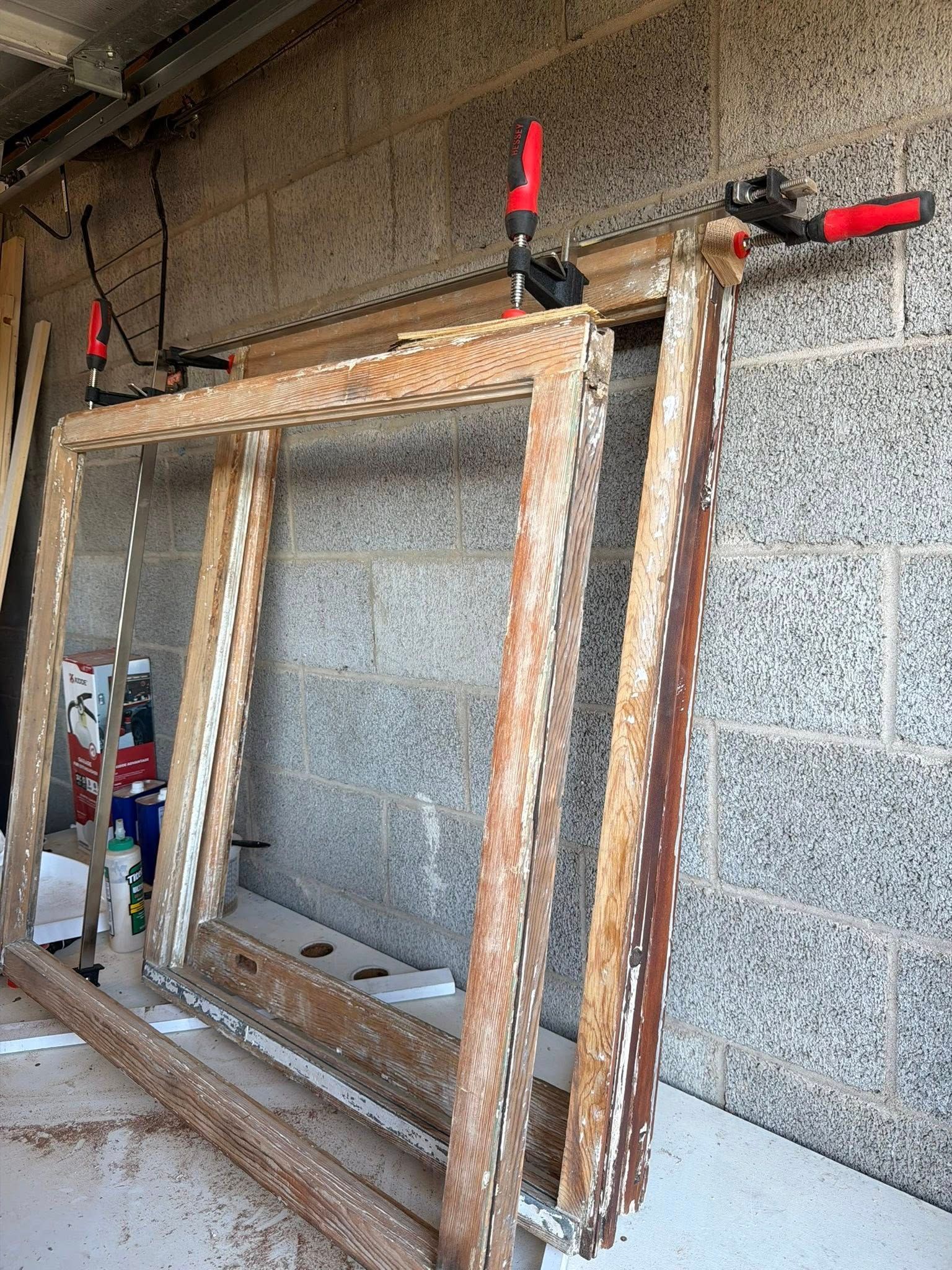 Partially built wooden window frames clamped to a concrete block wall in a construction area