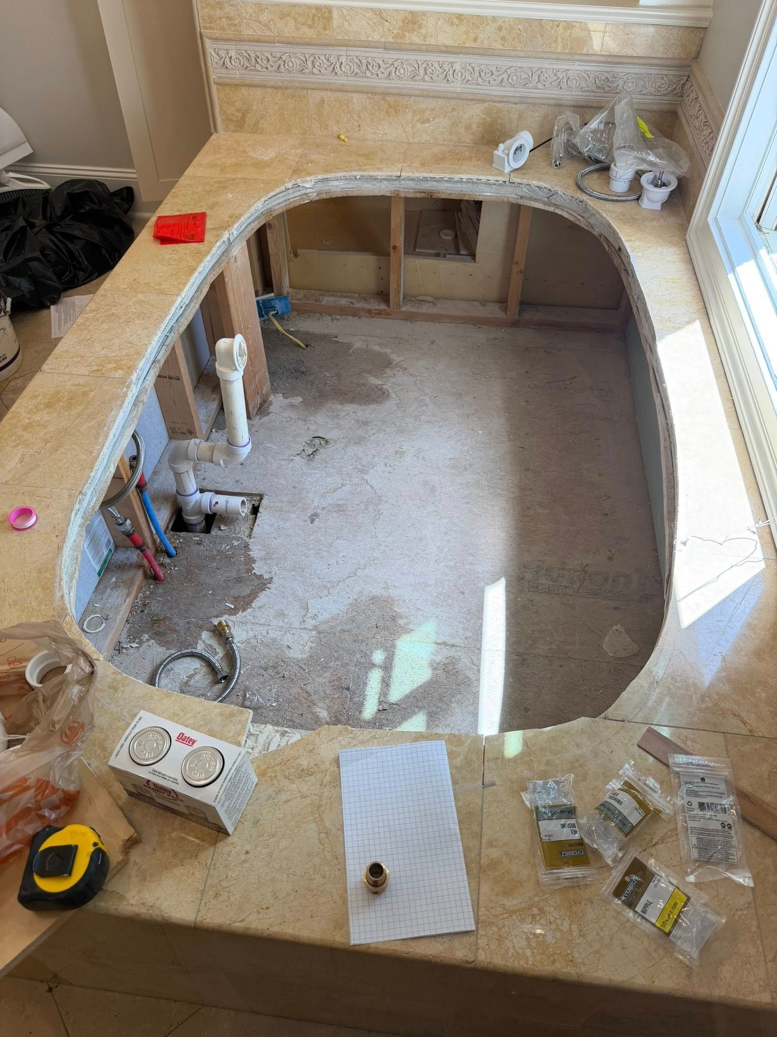 Large indoor room with a carpet being removed, exposing a sunken floor and renovation tools around the edges
