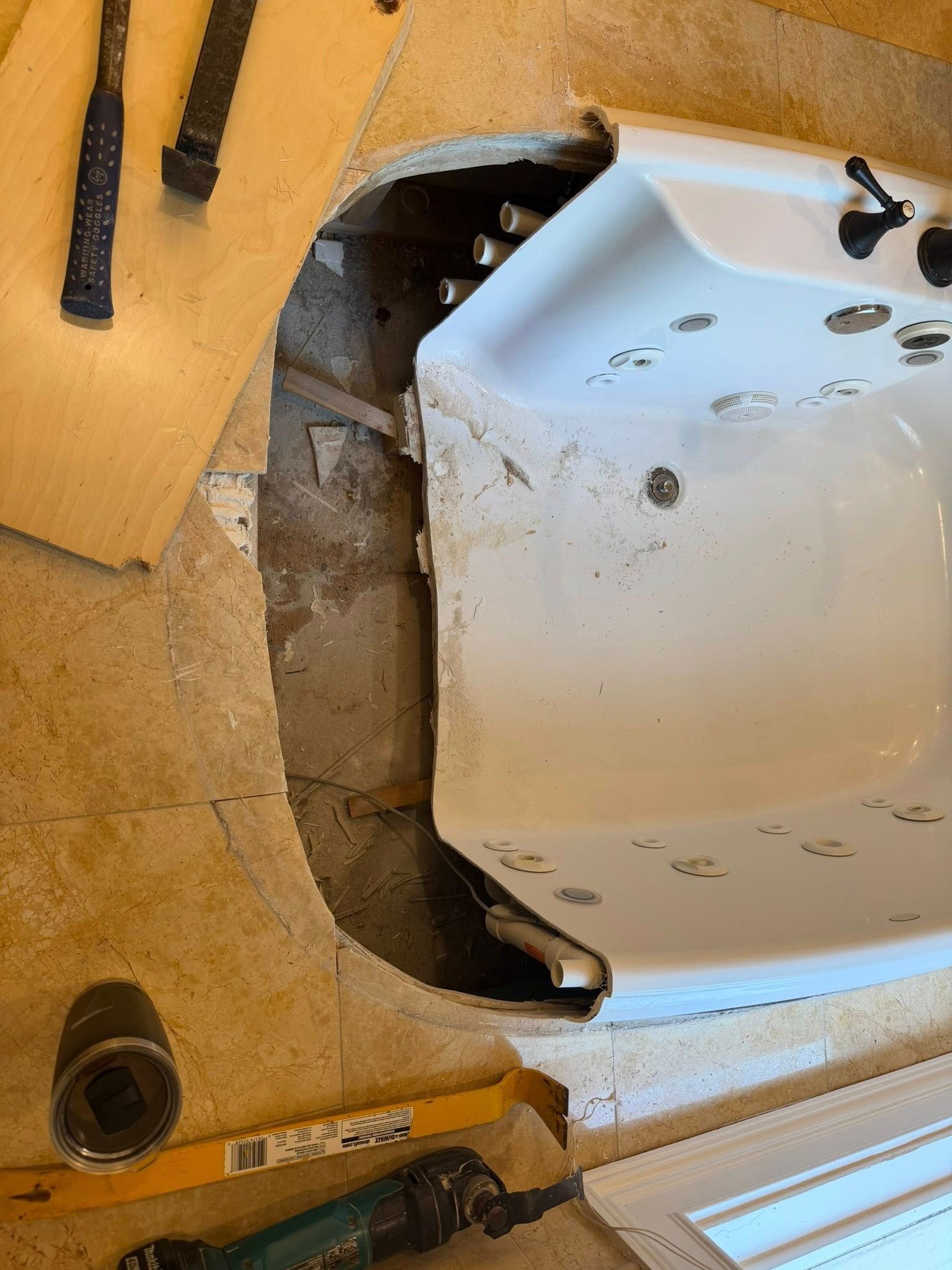 Close-up of a white car bumper near a yellow wall, showing damage and debris in a narrow gap