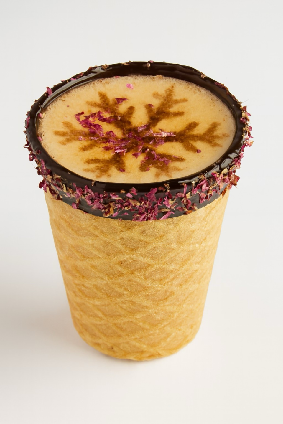 Decorated wafer cup filled with creamy dessert, topped with saffron-like garnish and a chocolate-rimmed edge
