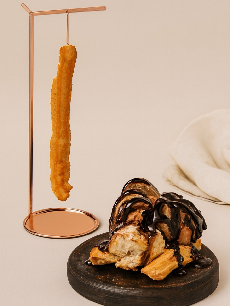 Crispy churro hanging over a metal stand beside a dessert plate with drizzled pastries