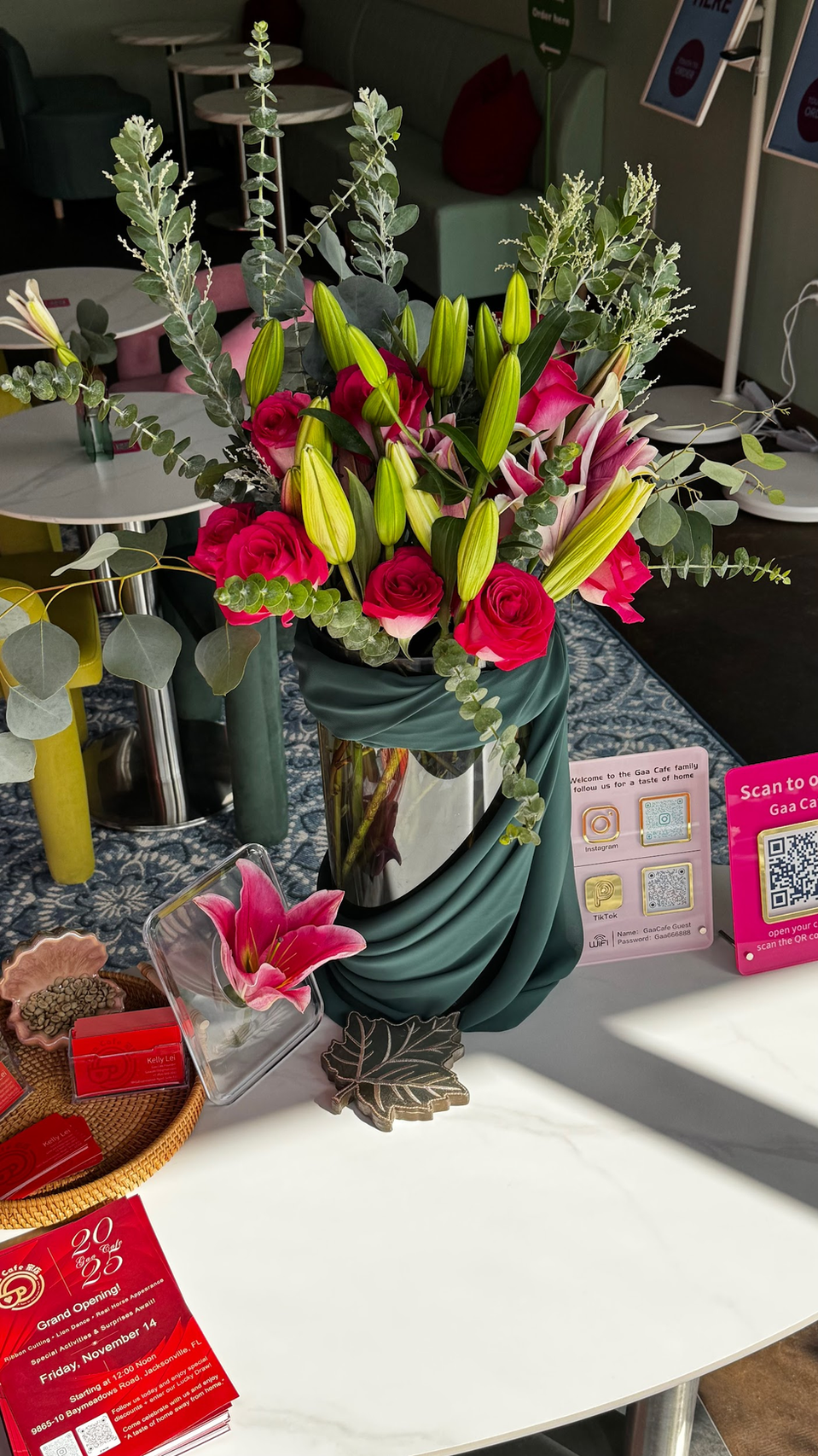Bright mixed flower arrangement with red, pink, yellow, and green blooms on a table in a sunlit room