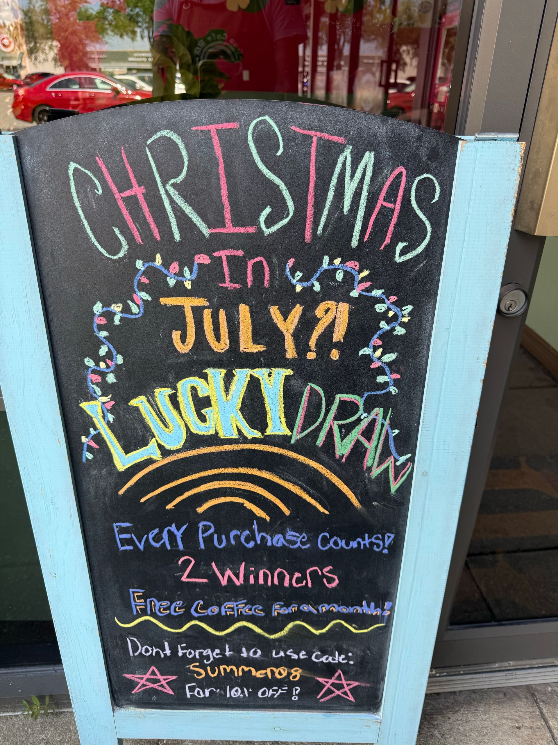 Colorful chalkboard sign advertising “Christmas in July” lucky draw with winner details and prize text