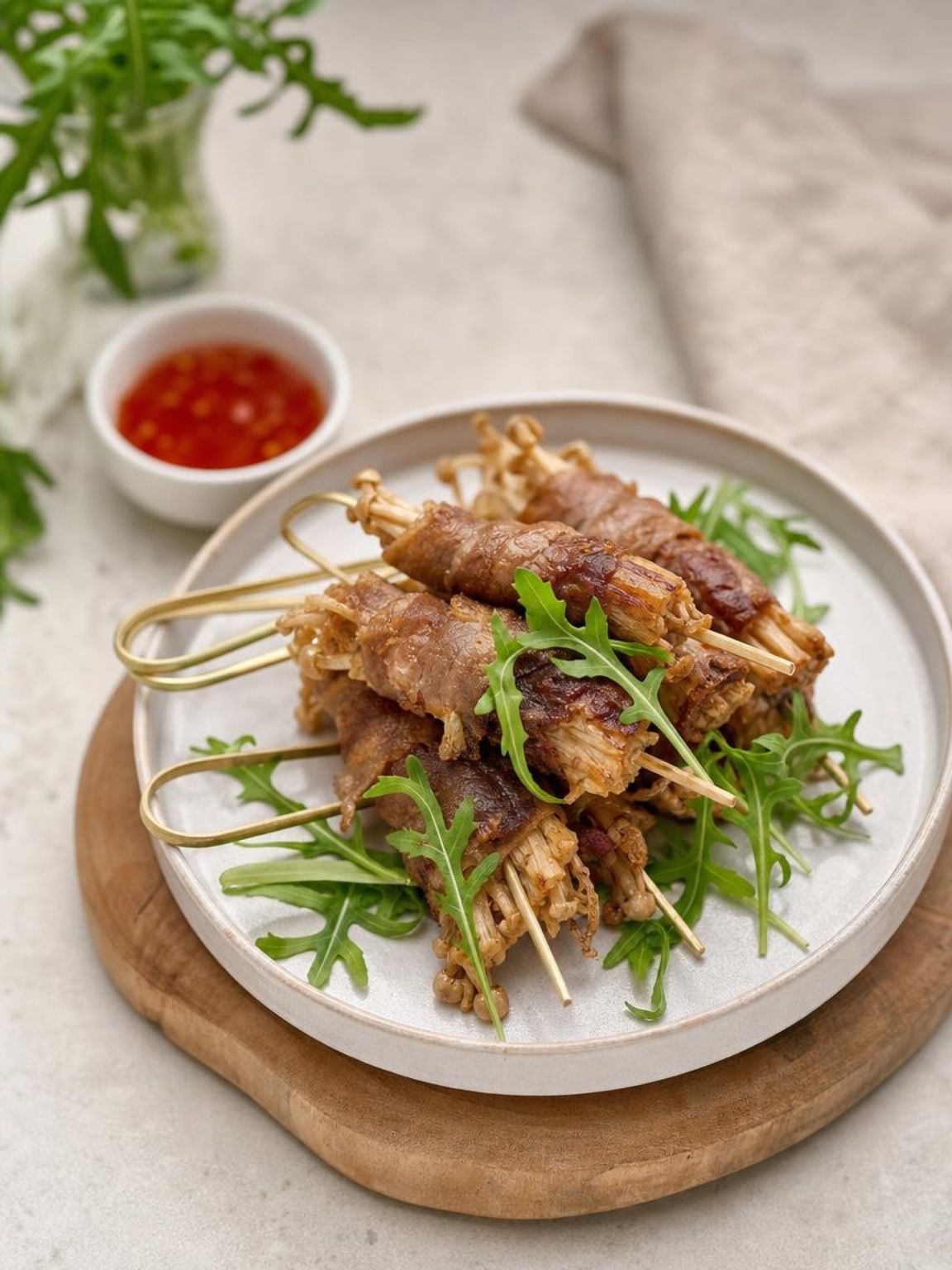Plate of grilled meat skewers with green garnish and dipping sauce on a wooden board